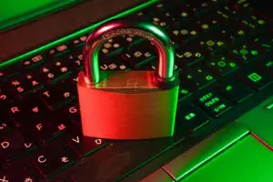 Bitunix A brass padlock sits on a laptop keyboard with Japanese characters, illuminated by green and red lighting, symbolizing cybersecurity, data protection, and the security offered by smart contract wallets.