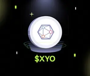 Bitunix A glowing coin with a geometric network symbol and orbiting rings, displayed under a spotlight on a dark grid background, with the text $XYO below in bright green.